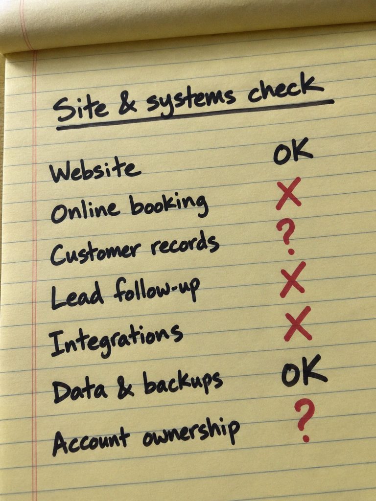 Handwritten site & systems check on a spiral notebook, several systems flagged